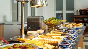A buffet setup with various food items and a salad bowl. - Sujet Beach Hotel &Apartment by Haviland (Da Nang)