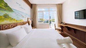 A hotel room with a large bed, a desk, a chair, a TV, and a mural of a coastal scene. - Sujet Beach Hotel &Apartment by Haviland (Da Nang)