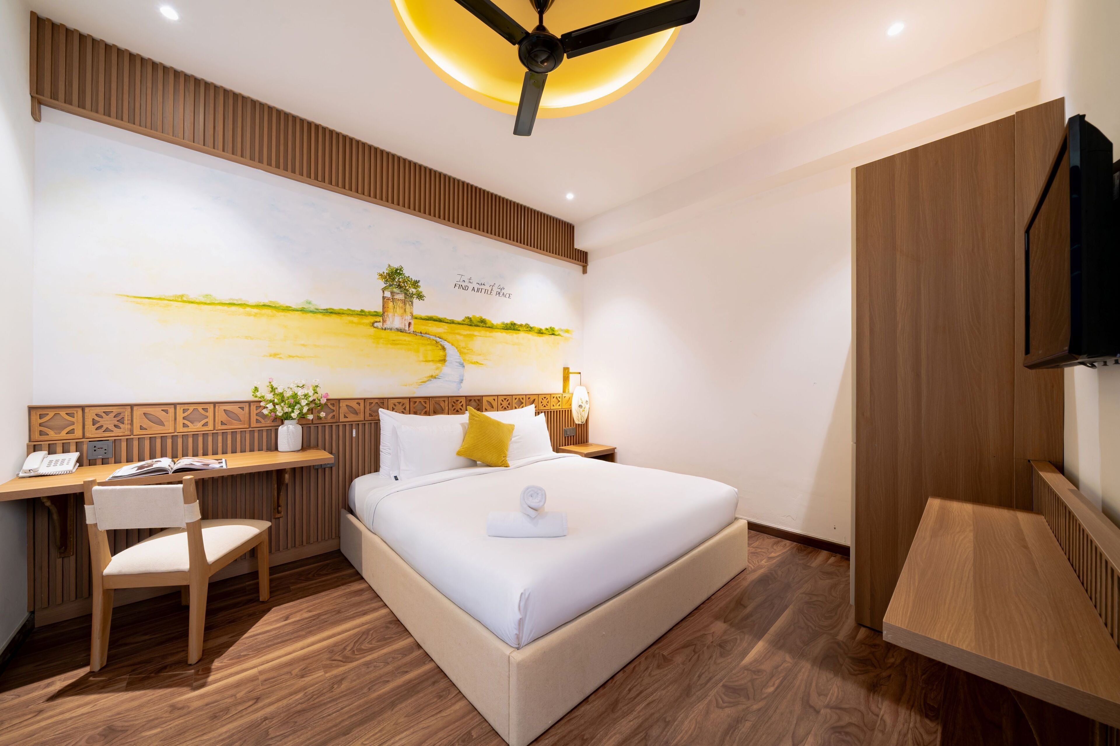 A modern hotel room with a large bed, a desk, a chair, and a TV.