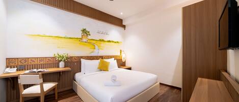 A modern hotel room with a large bed, a desk, a chair, and a TV.