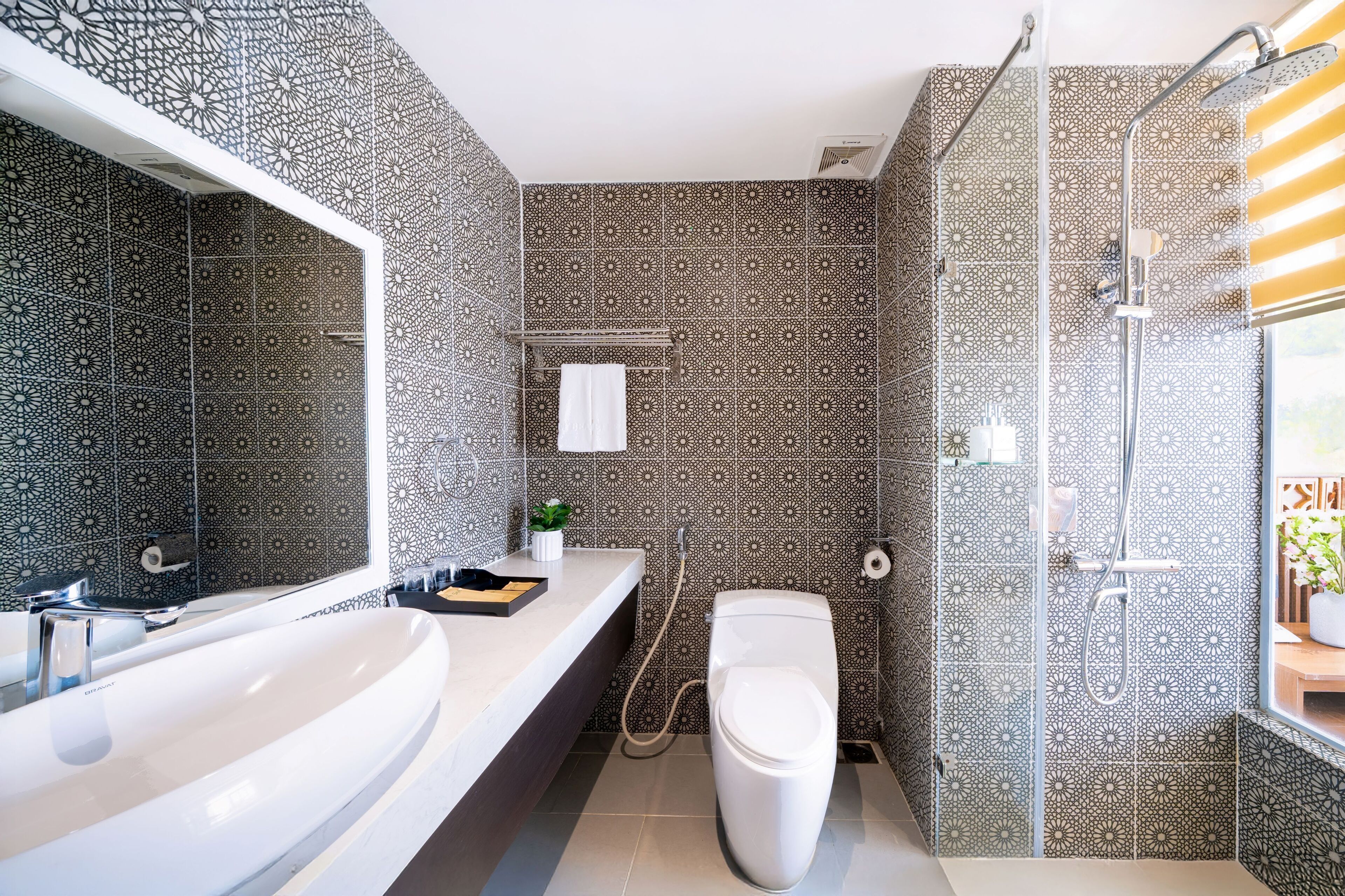 A modern bathroom with a large white sink, a toilet, and a shower area.