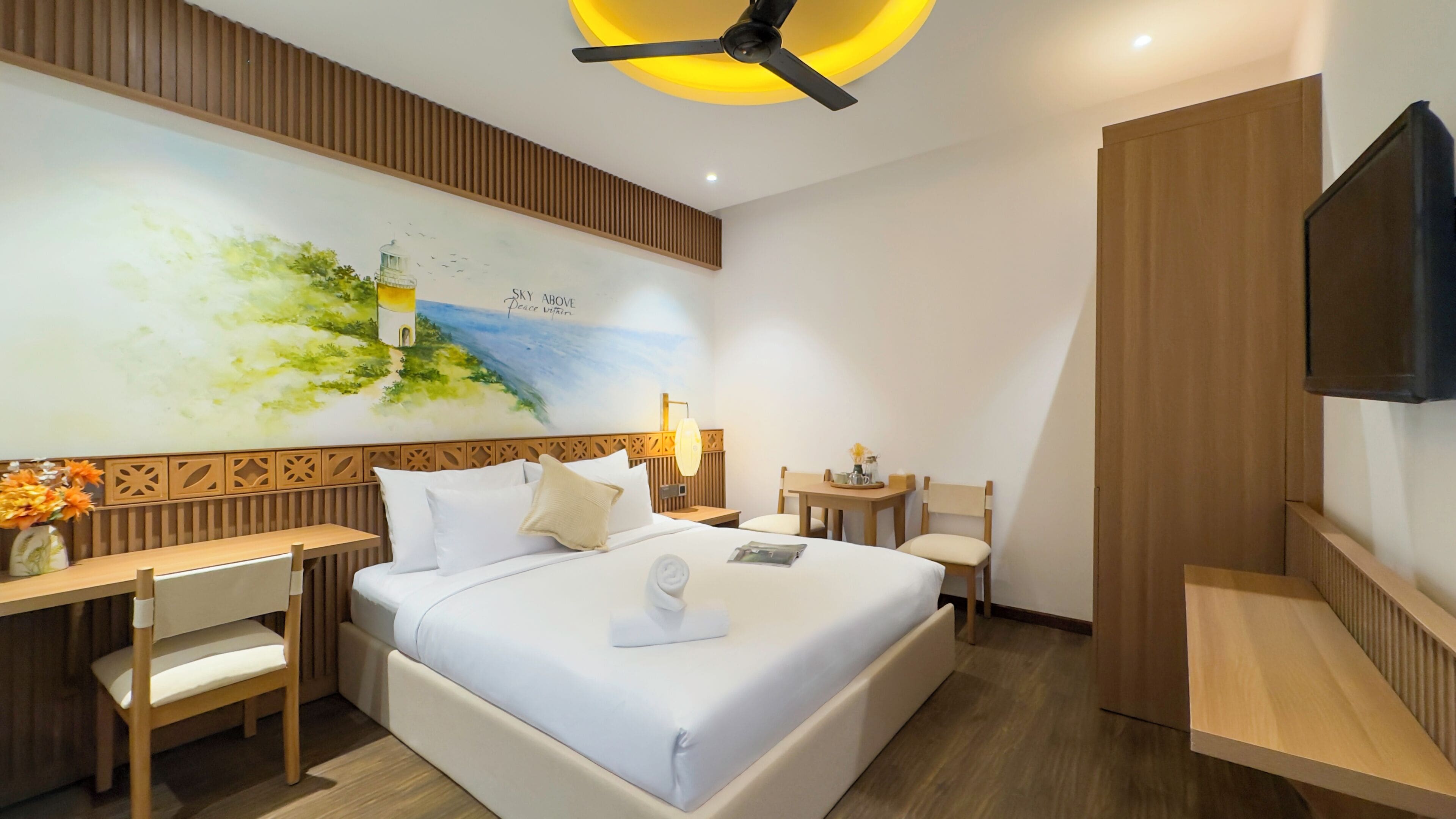 Una habitación de hotel moderna con una cama grande, un escritorio, una silla y un televisor montado en la pared.