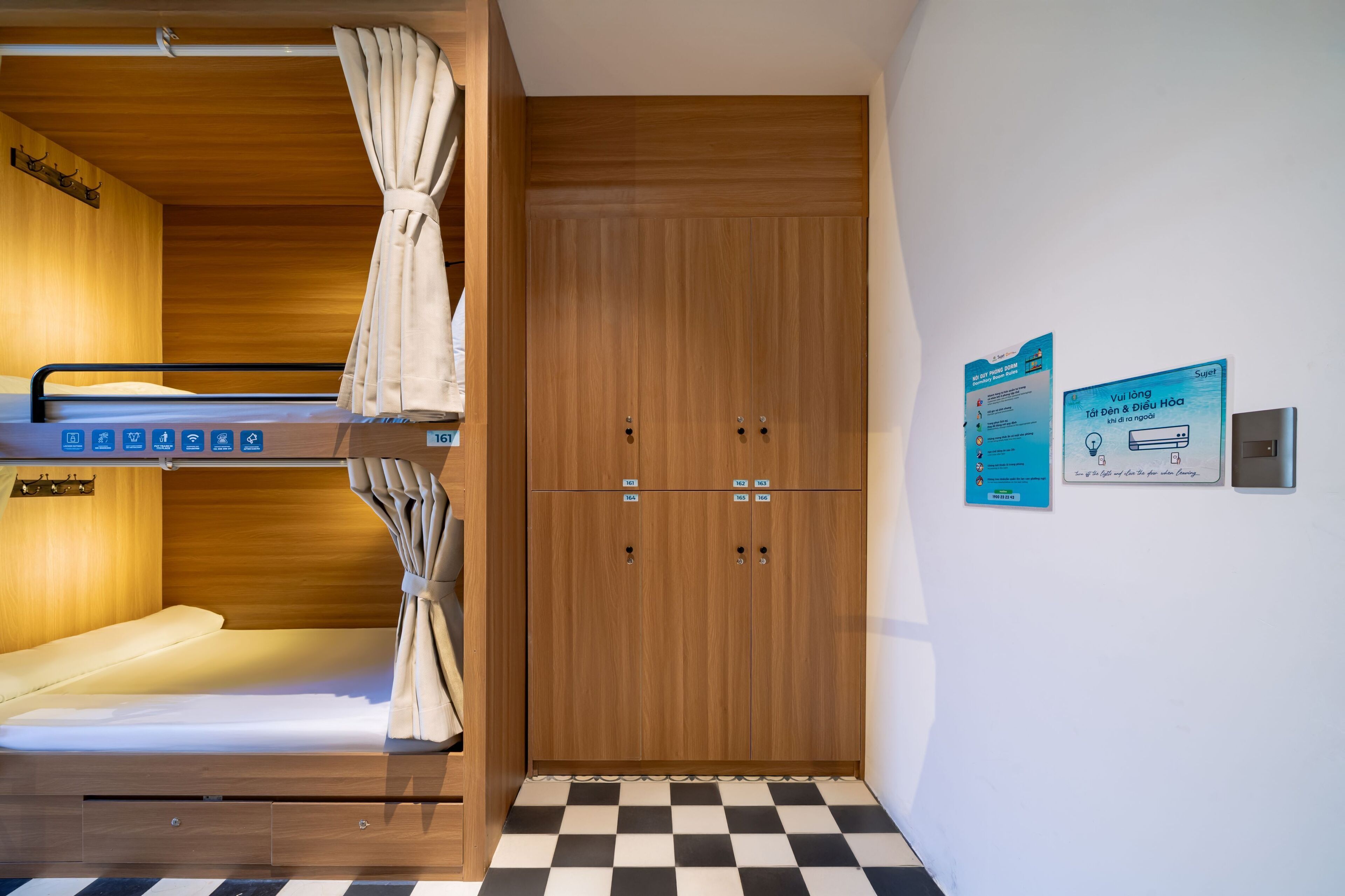 Habitación con literas, un armario de madera y piso de cuadros.