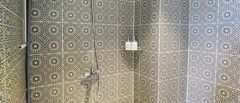 A shower with a geometric tile pattern and a handheld showerhead.