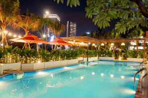 A swimming pool with surrounding palm trees and a covered area with umbrellas. - Sujet Beach Hotel Da Nang By Haviland (Da Nang)
