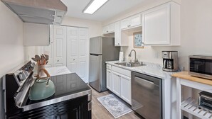 Een moderne keuken met witte kasten, roestvrijstalen apparatuur en een inbouwmagnetron.