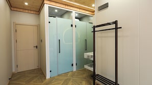 Un couloir avec un plafond en bois, un banc et une pièce séparée par une paroi de verre, elle aussi équipée d’un banc.
