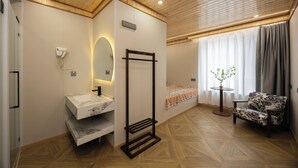 Une salle de bain moderne avec un plafond en bois, un lavabo en marbre, un porte-serviettes et une chaise près d’une fenêtre ornée de rideaux.