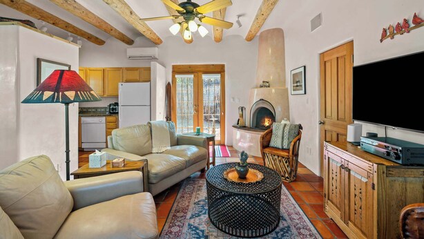 A cozy living room with a sofa, coffee table, and fireplace. There is a television and a wooden cabinet with a TV stand. - Walk to Plaza and Railyard, Fire Pit (Santa Fe)