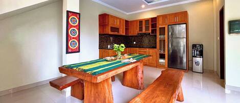 A modern kitchen with wooden cabinets, a stainless steel refrigerator, and a dining table with benches.
