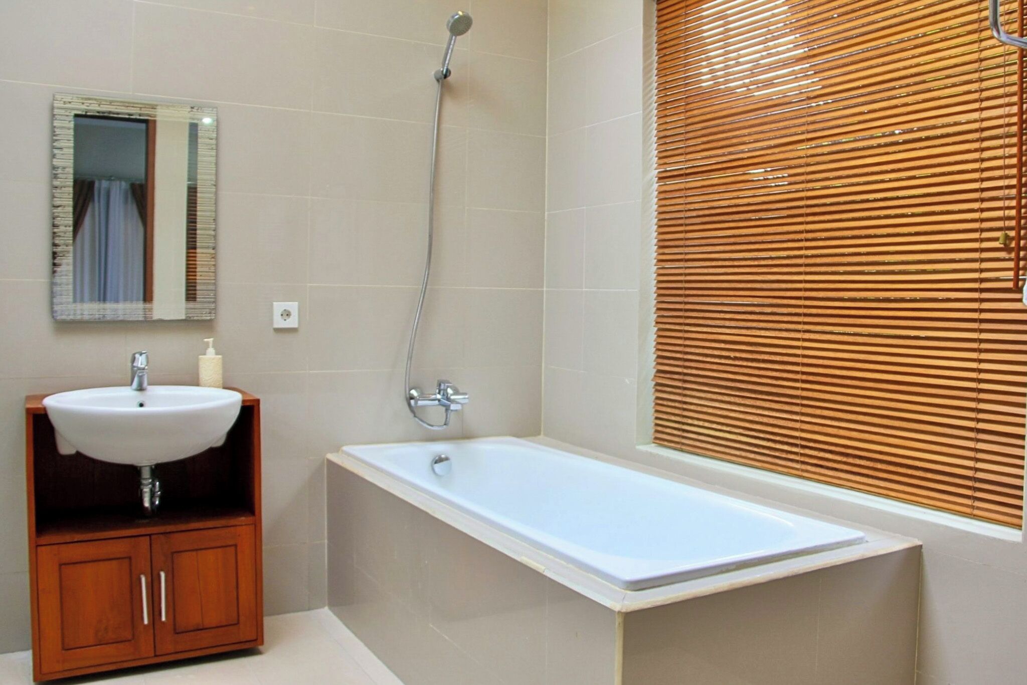 A bathroom with a white sink, wooden cabinet, and a bathtub.