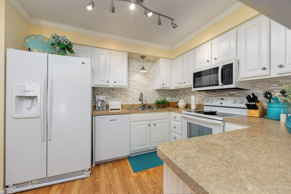 A modern kitchen with white cabinets, a granite countertop, a built-in microwave, and a stainless steel range hood. - Beach Access - Cozy 2-BD Pet Friendly Kitty Hawk Condo with pool, W&D, tennis (Kitty Hawk)
