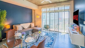 Una sala de estar moderna con un sofá, una mesa de centro de vidrio y un televisor montado en la pared.