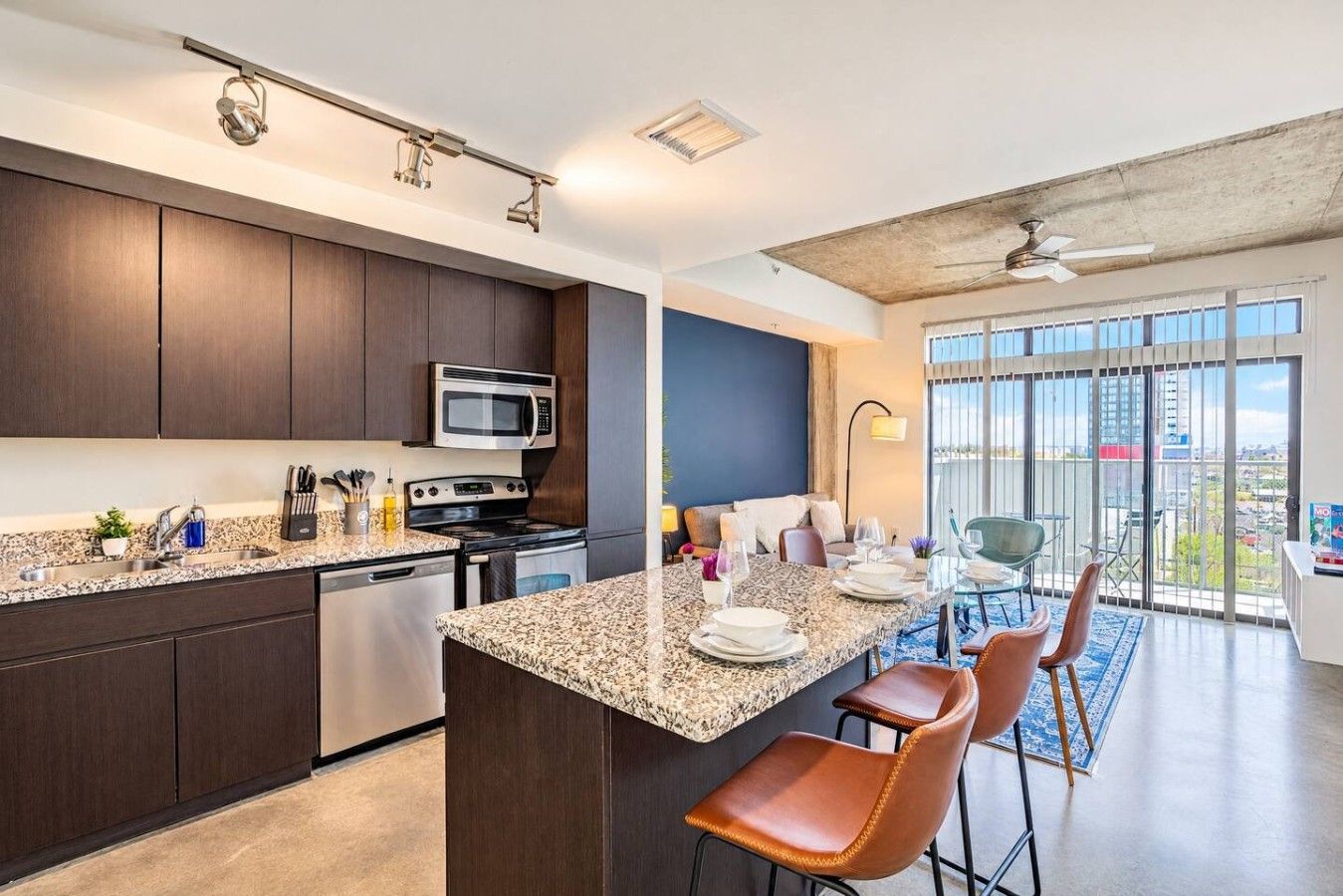 A modern kitchen with dark wood cabinets, stainless steel appliances, and a granite countertop.