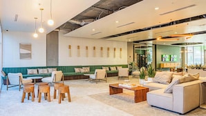 Un vestíbulo moderno con un sofá verde, sillones blancos y una mesa de centro de madera.