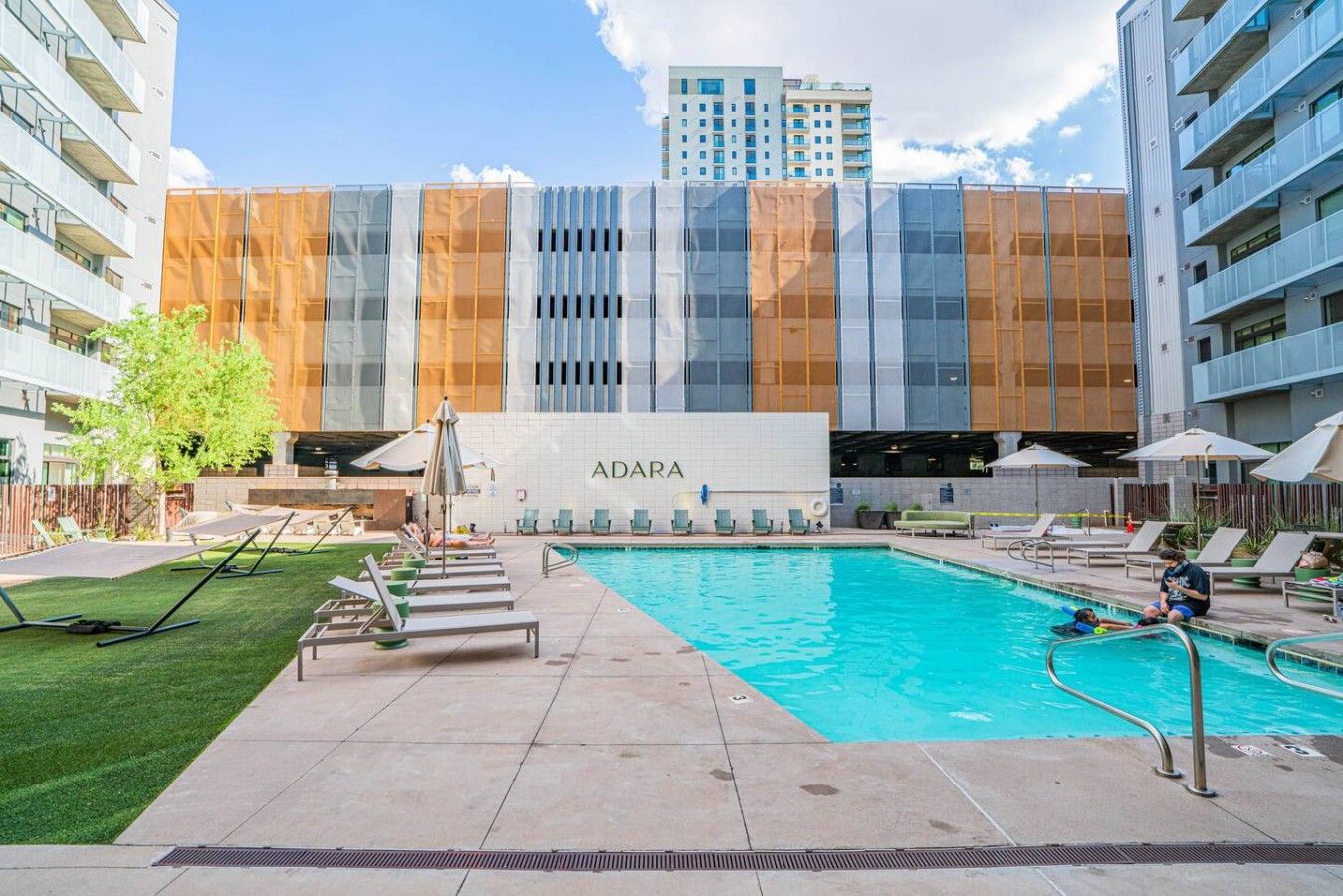 Un edifici modern amb piscina, gandules i para-sols.