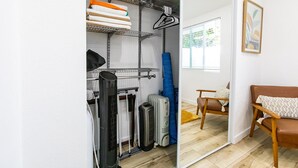 Une petite pièce comprenant un lit, une chaise et un meuble de rangement avec des étagères et un radiateur.