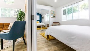 Une chambre moderne avec un grand lit, un fauteuil bleu, un canapé et une plante en pot.