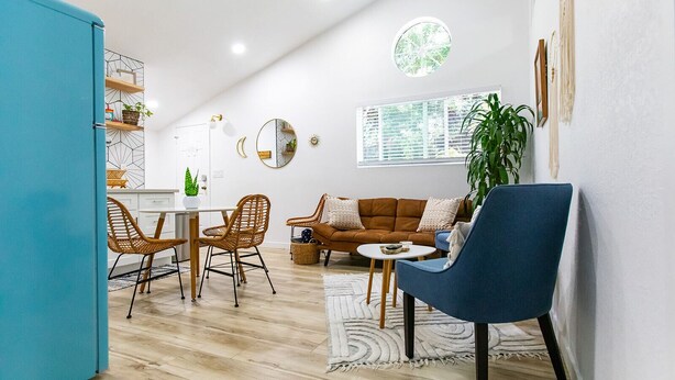 Une cuisine moderne avec un coin repas, comprenant un meuble bleu, des chaises en osier, un canapé marron et un fauteuil bleu.