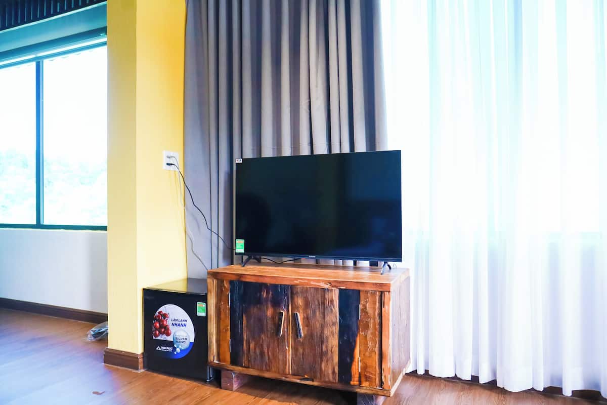 Egy televízió áll egy fa szekrényen, a padlón pedig egy konnektor és egy kábelcsatlakozó doboz található.