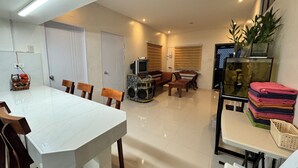 Ein geräumiger Wohnbereich mit Esstisch, Stühlen, einer Couch und einem TV-Schrank.