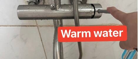 Eine Dusche mit einem Bedienfeld zur Einstellung der Wassertemperatur, das eine Regulierung für warmes Wasser ermöglicht.