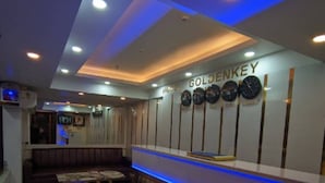A hotel reception area with a modern design, featuring a reception desk, a wall-mounted clock, and a blue-lit reception counter. - Hotel Goldenkey (Kolkata)