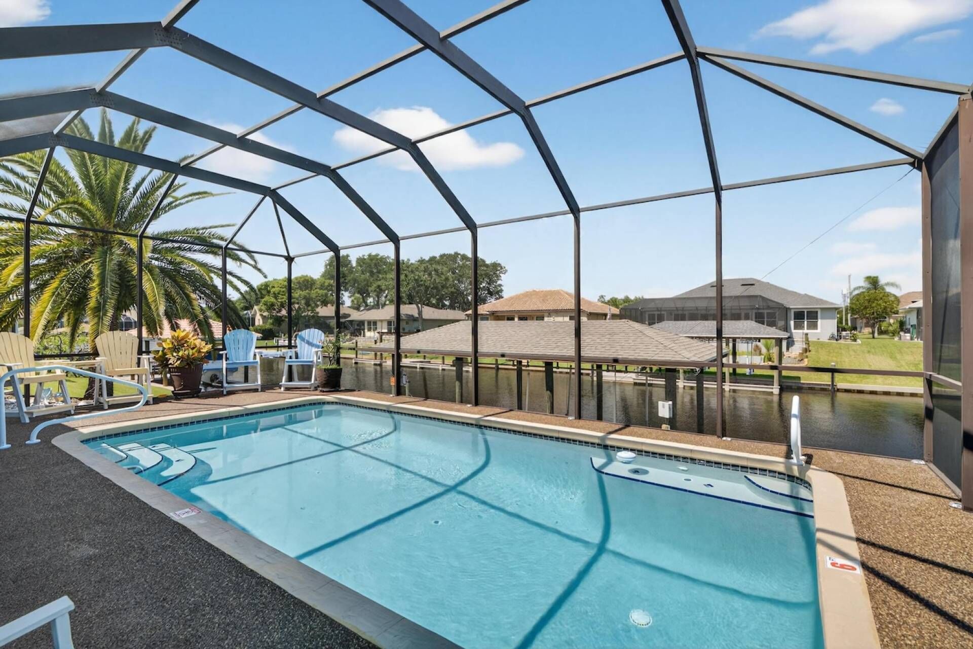 En swimmingpool med fri utsikt över det omgivande området, inklusive hus och palmer.