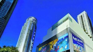 Un bâtiment moderne orné d’une grande fresque murale et portant l’inscription « Bienvenue au Miami World Center ».