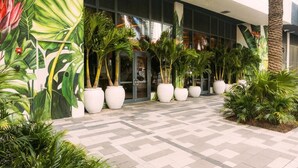 Une entrée moderne, agrémentée de grands pots de plantes et d’un chemin piétonnier carrelé.