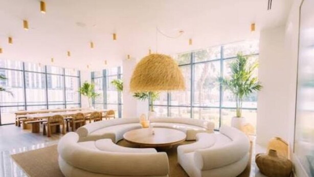 Un espace de détente moderne avec un aménagement circulaire des sièges, de grandes fenêtres et un luminaire suspendu.