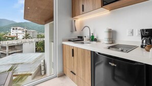 A modern kitchen with a built-in dishwasher, a coffee maker, and a view of a building and mountains.