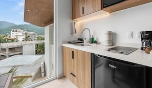 A modern kitchen with a built-in dishwasher, a coffee maker, and a view of a building and mountains.