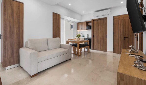A modern living room with a sofa, a dining table, and a TV.