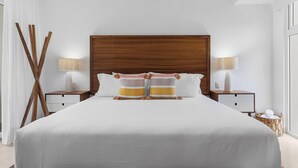 A large bed with a wooden headboard, two bedside tables with lamps, and a wicker basket on the floor.