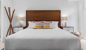 A large bed with a wooden headboard, two bedside tables with lamps, and a wicker basket on the floor.