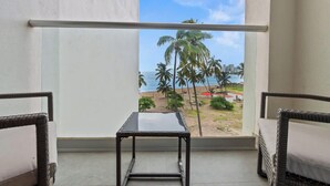 A balcony with a view of a beach, palm trees, and a cityscape.