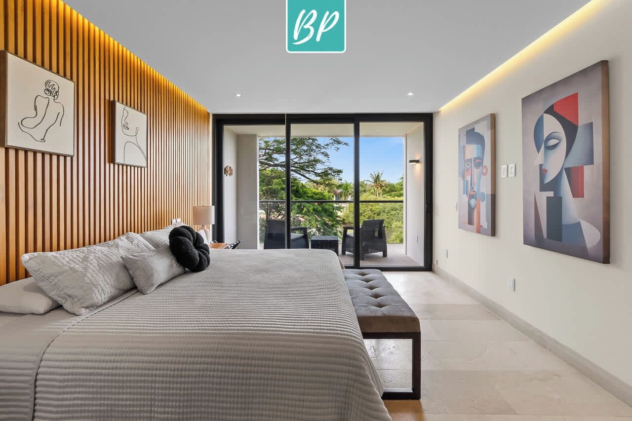 A modern bedroom with a bed, a bench, and artwork on the walls.