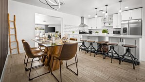 Een moderne keuken met een centraal kookeiland, barstoelen en roestvrijstalen apparatuur.