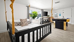 Een slaapkamer met een hemelbed, een bureau met een computer en een tafelvoetbaltafel.