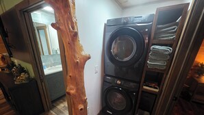Une petite buanderie équipée d’un lave-linge et d’un sèche-linge Samsung, dotée d’un plancher en bois et décorée d’un tronc d’arbre rustique.