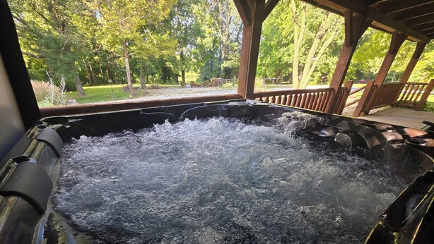 Un bain à remous où l’eau bouillonne, entouré d’une terrasse en bois et d’arbres.