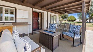 A covered patio area with a sofa, chairs, and a dining table.