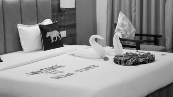 Habitación de hotel con cama, almohadas, una decoración de cisne y un cartel de bienvenida.