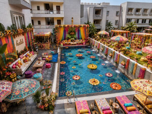 A rooftop pool area with a seating arrangement, surrounded by colorful umbrellas and floral decorations.