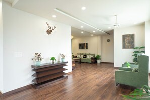 Una sala moderna con piso de madera, sofá verde y un adorno de pared.