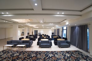 A spacious conference room with rows of chairs and tables, a patterned carpet, and a modern ceiling design. - Savanna Retreat by Nuva Stayz (Ramnagar)