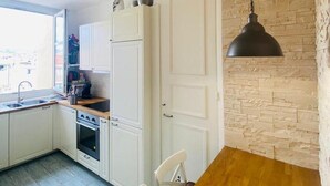 A modern kitchen with white cabinets, a wooden dining table, and a hanging pendant light.