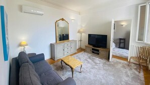 A living room with a sofa, a coffee table, a TV, and a mirror.
