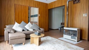 A modern living room with a sofa, a small round table, and a portable heater. - FURANO RELAX STAY A (Furano)